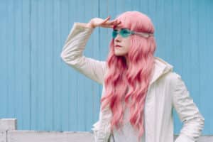 In diesem Beispiel zur generativen Suchmaschinenoptimierung steht eine Person mit langen rosa Haaren und einer blauen Schwimmbrille, die ihre Augen schützt, vor einer blauen Wand.